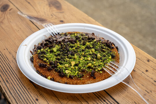 Knafeh served on a disposable plate with plastic forks.
Knafeh is a typical Arab dessert found in several Middle Eastern countries.
