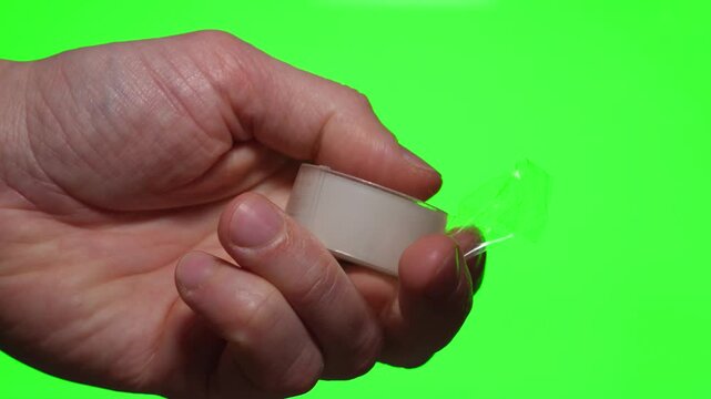 A roll of clear adhesive tape on a green isolated background.
Close-up of the adhesive tape