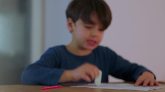 Young boy focused on homework at table reading problem carefully and erasing mistake while concentrating on finding correct solution