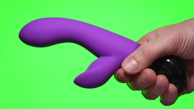 Pink dildo on a green background.
Sex toy in hand.
Pink rabbit vibrator.