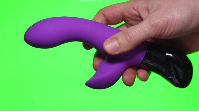 Pink dildo on a green background.
Sex toy