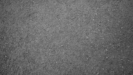 Detailed high-angle texture of rough dark gray asphalt road.