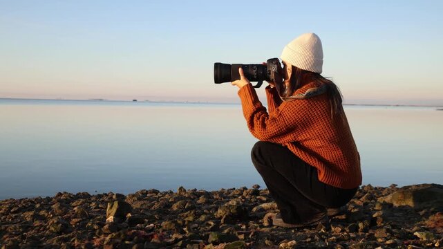 A 36-year-old female solo traveler using a telephoto lens to capture the sunrise at Ebro Delta, Tarragona, Spain.