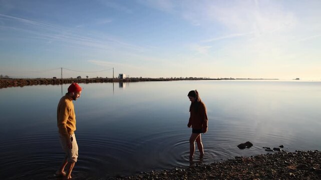 Happy young couple laughing and splashing in the shallow, still water of the Mediterranean in Delta Ebro, Spain.