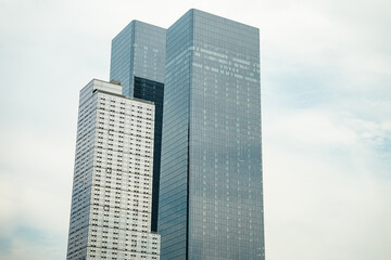 Obraz premium Tall reflective skyscrapers dominate the Manhattan skyline against a pale sky. The scene emphasizes contemporary architecture and dense urban development in New York City.