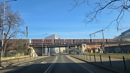Freight train on steel column viaduct over city street
