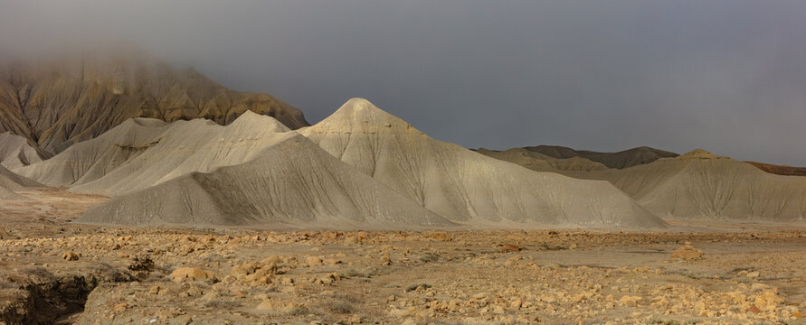 The sun breaks through the low-hanging clouds to accent the lunar-like landscape of the Caineville Badlands near Capitol Reef National Park, Utah.