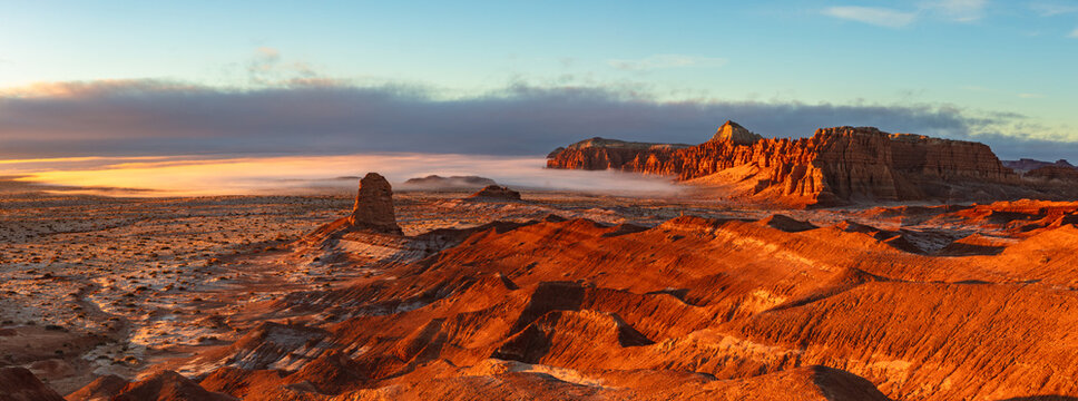 This stunning sunrise panorama of Goblin Valley State Park, Utah, features the orange glowing cliffs with a low cloud inversion creeping in.
