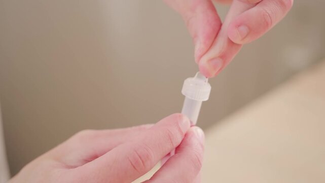 Male fingers closeup, man performing self-administered medical test pricking finger and collecting blood in tube, fingertips Personal health data, rapid diagnostic at-home test