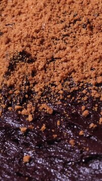 Vertical 4K Close Up of Speculoos Cookie Crumbs Pouring and Covering Brownie Batter