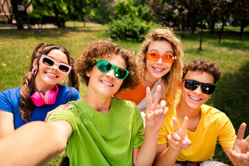 Diverse group of youthful friends posing outdoors under natural sunlight wearing casual fashion...
