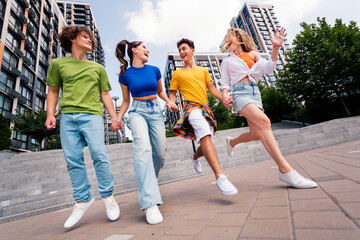 Group of young friends enjoying outdoor time together in an urban setting showing casual style and...