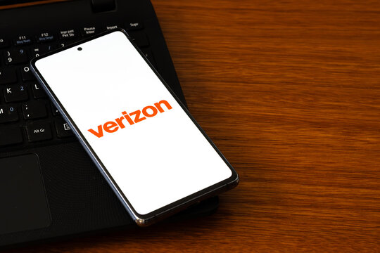 Punta Arenas, Chile &ndash; March 05, 2026: A smartphone displaying the Verizon telecommunications logo on its screen, resting on a black laptop keyboard over a wooden desk surface