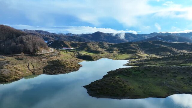 Aerial drone cinematic video of amazing artificial lake Aoou with beautiful nature and reflecting clouds near picturesque village of Metsovo surrounded by mountains of Pindus, Epirus, Greece