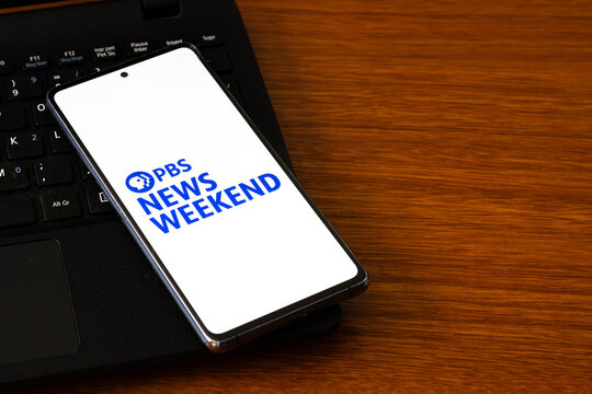 Punta Arenas, Chile &ndash; March 05, 2026: A smartphone screen displaying the PBS News Weekend logo in blue, resting on a black laptop keyboard over a wooden desk