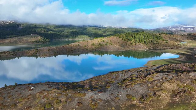 Aerial drone cinematic video of amazing artificial lake Aoou with beautiful nature and reflecting clouds near picturesque village of Metsovo surrounded by mountains of Pindus, Epirus, Greece