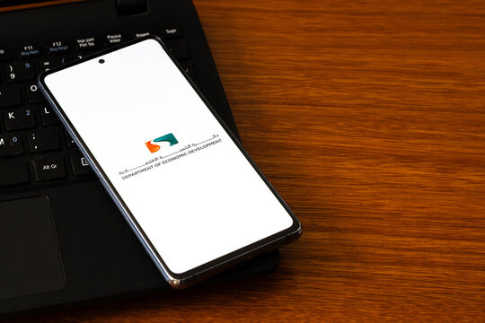 Punta Arenas, Chile &ndash; March 05, 2026: A smartphone screen displaying the Abu Dhabi Department of Economic Development logo, resting on a black laptop keyboard