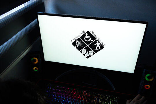 Punta Arenas, Chile &ndash; March 07, 2026: A desktop PC monitor showing various disability access icons in a dark room with a backlit gaming keyboard