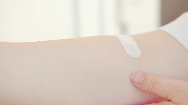 arm with patch on skin, indicating medical treatment, medical care, adhesive bandage, band-aid after blood donation, plaster after giving blood for medical tests and laboratory analysis