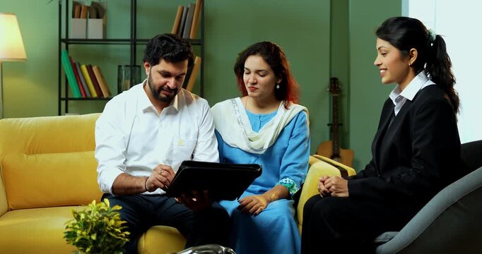 Indian young happy couple signing and shaking hands after discussing financial document or legal matters with female corporate consultant during home meeting to finalize their agreement.