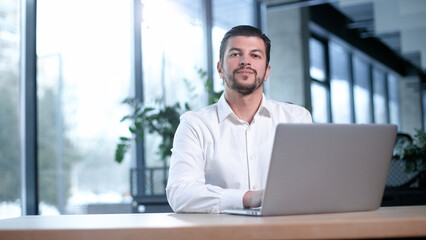 Fototapeta premium A man is sitting at a desk with a laptop in front of him