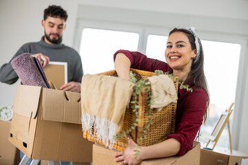 Young happy couple carrying cardboard boxes into their new empty apartment.