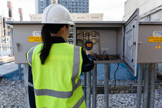Engineer scanning substation marshalling cabinet with infrared thermal camera