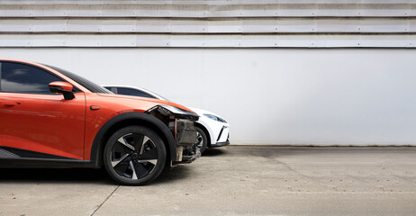 Damaged orange car waiting for repair at auto body shop.