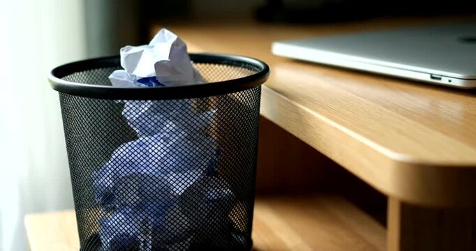 Crumpled Paper in Trash Can Near Laptop.
