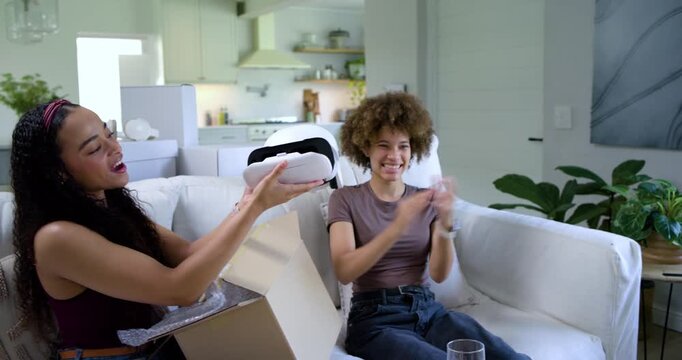 African American women reaching into box on couch, unboxing white VR headset and showing to phone