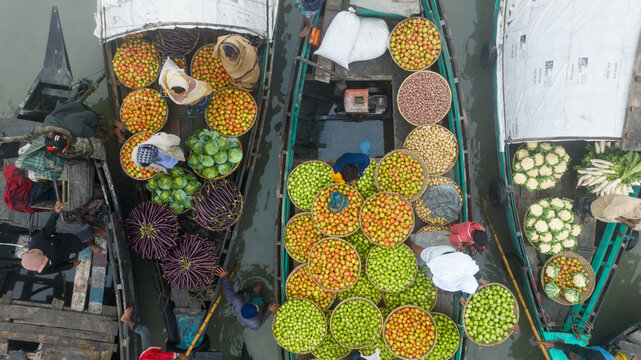 Aerial view of vibrant fruits and vegetables piled high on boats create a bustling market scene along the Baishmouja bazar main road, Brahmanbaria, Chittagong Division, Bangladesh.