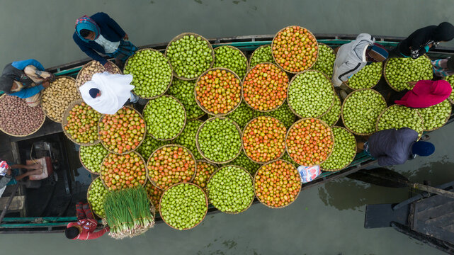 Aerial view of boats laden with vibrant green and reddish-yellow fruits, creating a mosaic of colors on the water at Baishmouja bazar main road, Brahmanbaria, Chittagong Division, Bangladesh.