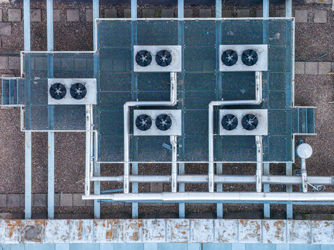 Aerial view of multiple air conditioning units and ventilation systems on a rooftop, creating a geometric composition of metal, pipes, and fans, Warsaw, Masovian Voivodeship, Poland.