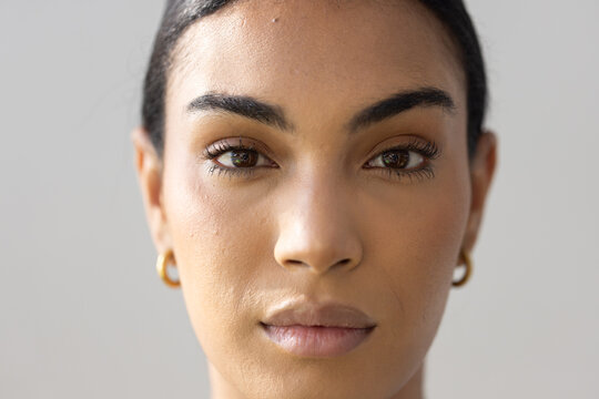 Adult African woman posing for head-and-shoulders portrait in studio, wearing gold hoop earrings