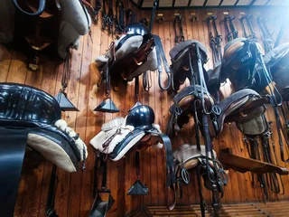 Fototapete Reiten Wide assortment of equestrian tack and saddles in vintage wooden stable  © Nadezda Ledyaeva