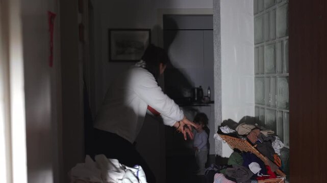 Mother making shadow puppets on kitchen wall to amuse toddler, candid family bonding moment filled with laughter and playful connection at home