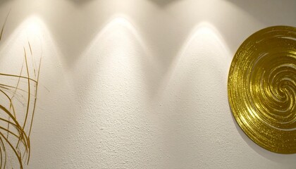 Trzy ciepłe światła reflektorów oświetlają białą teksturowaną ścianę obok złotej dekoracji ściennej.