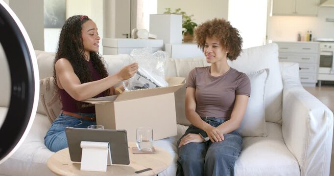 African American women unboxing new package on couch tearing bubblewrap revealing device for vlog