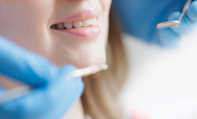 Naklejka premium Female young caucasian patient smiling during dental checkup with blue gloved dentist, white light