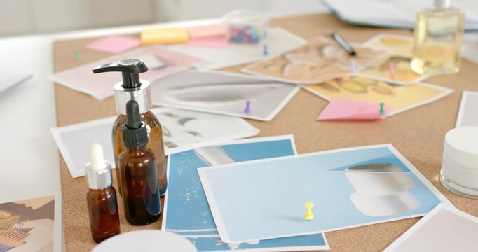 Amber bottle cluster sitting by blue prints on cork camera pulling back revealing desk, copy space