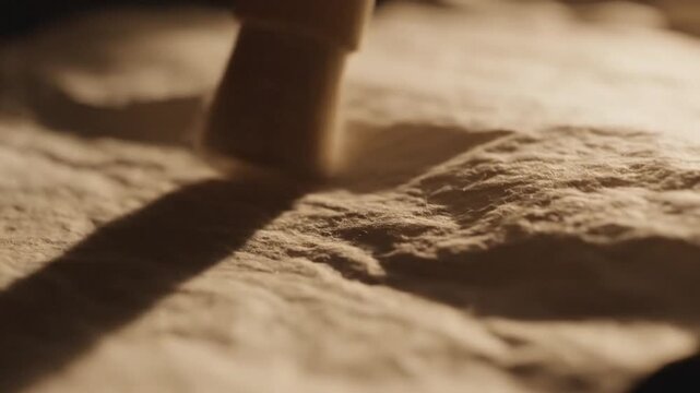 Close-up of a textured surface with a cylindrical object casting a shadow on it in warm lighting.