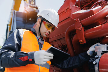 Young caucasian male engineer using tablet for repair engine of industrial truck on construction site © Parilov