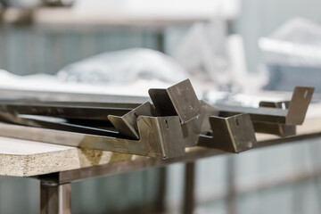 Obraz premium Finished metal parts and bent steel components on a workbench in a manufacturing workshop.