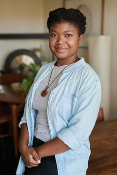 Smiling young African woman standing in her living room