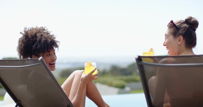 Diverse women friends swimsuit-clad poolside left woman smiling toasting with yellow drinks sipping