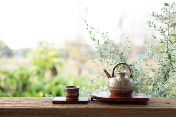 Ancient rustic teapot and cup on wooden table with outdoor view