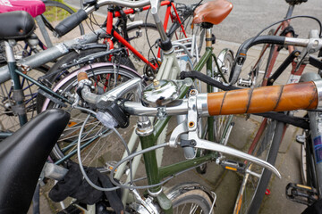 Obraz premium Close-up of tightly packed bicycles with overlapping handlebars, grips, and accessories creating a chaotic, urban parking scene.