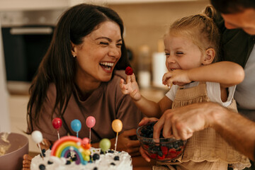 Mother and child celebrating birthday with berries and cake