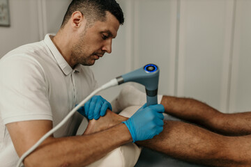 Physiotherapist using shockwave therapy treating foot pain