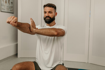 Male client performing arm stretch for shoulder rehabilitation